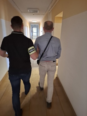 policjant podczas doprowadzania zatrzymanego