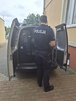 policjant podczas doprowadzania zatrzymanego