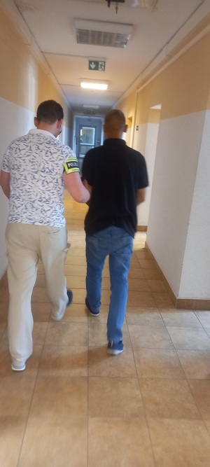 policjant podczas doprowadzania zatrzymanego