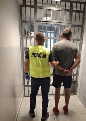 policjant podczas doprowadzenia zatrzymanego