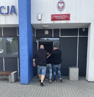 policjanci podczas doprowadzenia zatrzymanego