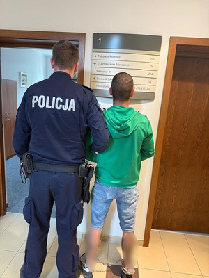 policjant podczas doprowadzania zatrzymanego