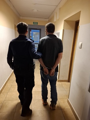 policjant podczas doprowadzenia zatrzymanego