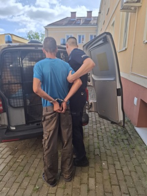 policjant podczas doprowadzania zatrzymanego