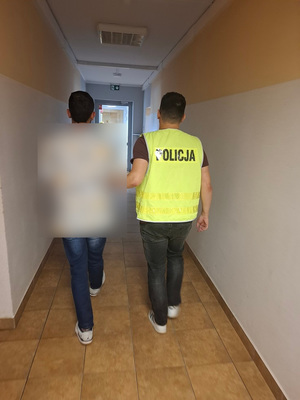 policjant podczas doprowadzania zatrzymanego