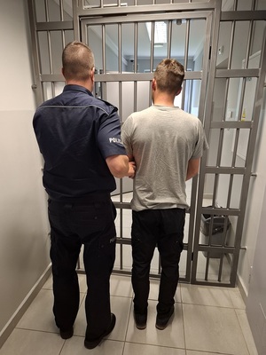 policjant podczas doprowadzania zatrzymanego