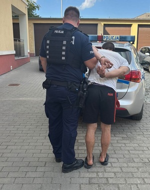 policjant podczas doprowadzania zatrzymanego