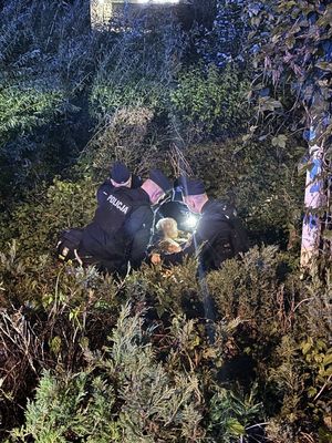 policjanci podczas udzielania I pomocy przedmedycznej odnalezionej kobiecie