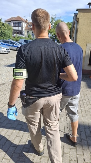 policjant podczas doprowadzania zatrzymanego