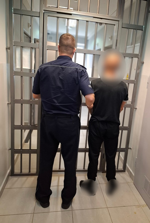 policjant podczas doprowadzania zatrzymanego