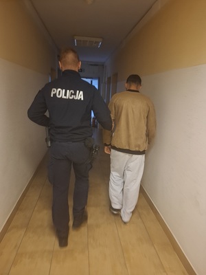 policjant podczas doprowadzania zatrzymanego