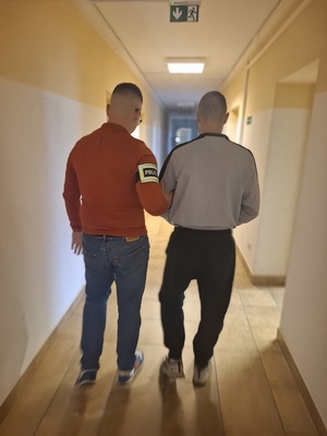 policjant podczas doprowadzania zatrzymanego