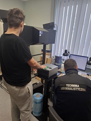 policyjny technik podczas czynności z zatrzymanym