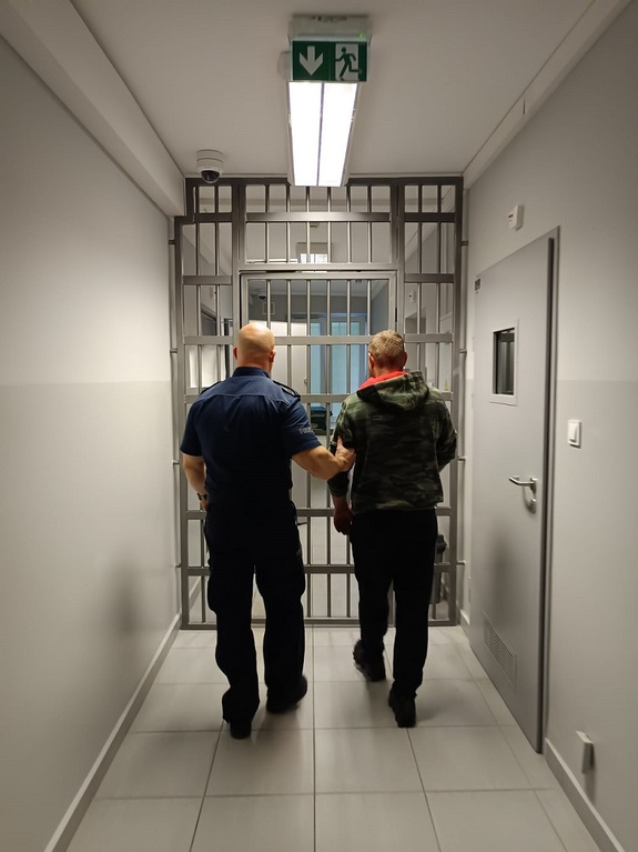 policjant podczas doprowadzania zatrzymanego