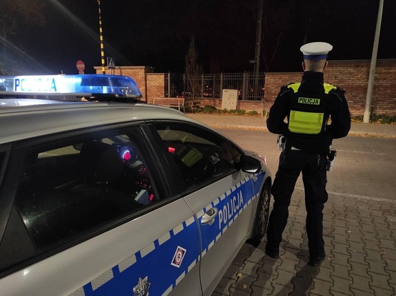 policjant przy radiowozie obok cmentarza