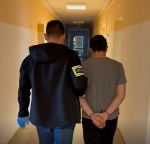 policjant podczas doprowadzania zatrzymanego