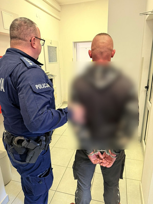 policjant podczas doprowadzania zatrzymanego