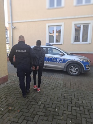 policjant podczas doprowadzania zatrzymanego