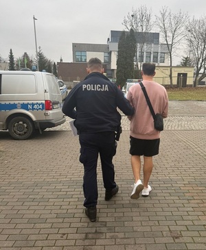 policjant podczas doprowadzania zatrzymanego