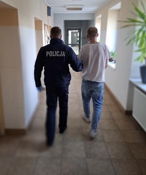 policjant podczas doprowadzania zatrzymanego