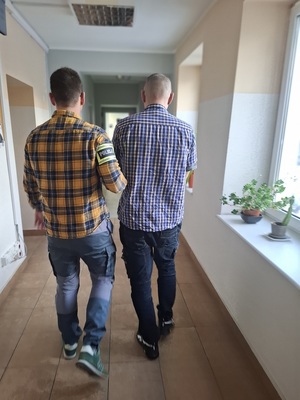policjant podczas doprowadzania zatrzymanego