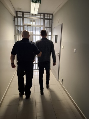 policjant podczas doprowadzania zatrzymanego