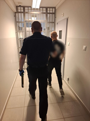 policjant podczas doprowadzania zatrzymanego