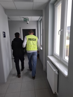 policjant podczas doprowadzania zatrzymanego