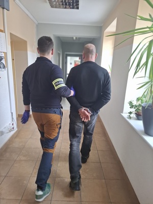 policjant podczas doprowadzania zatrzymanego