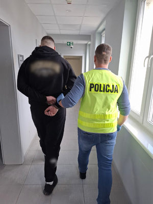 policjant podczas doprowadzenia zatrzymanego