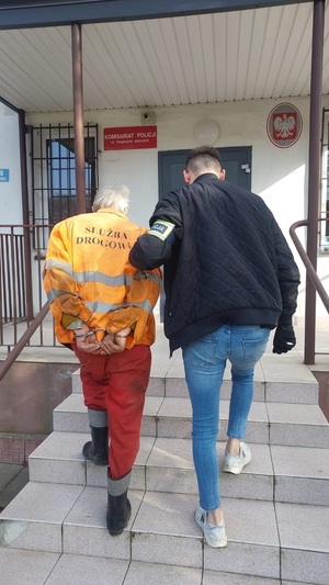 policjant podczas doprowadzania zatrzymanego