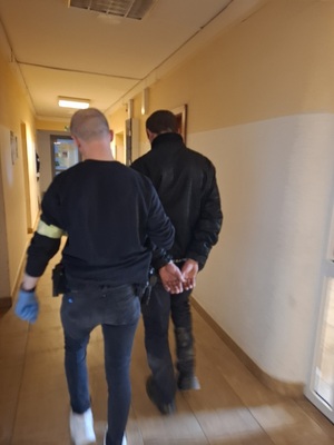 policjant podczas doprowadzania zatrzymanego