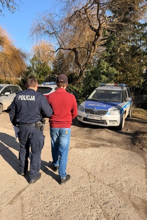 policjant podczas doprowadzania zatrzymanego