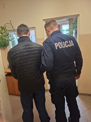 policjant podczas doprowadzenia zatrzymanego