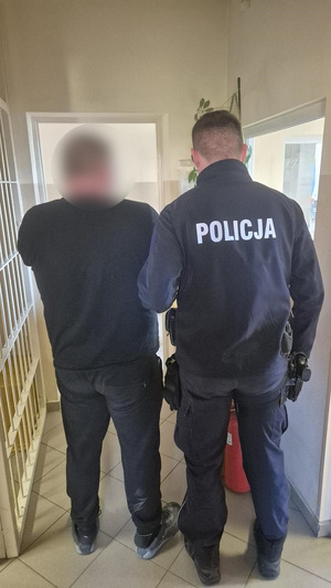 policjant podczas doprowadzania zatrzymanego