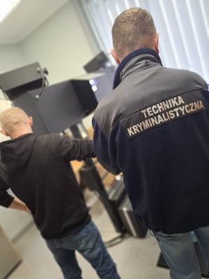 policyjny technik kryminalistyki podczas czynności z zatrzymanym