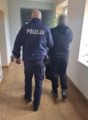 policjant podczas doprowadzania zatrzymanego