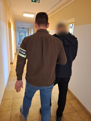 policjant podczas doprowadzenia zatrzymanego