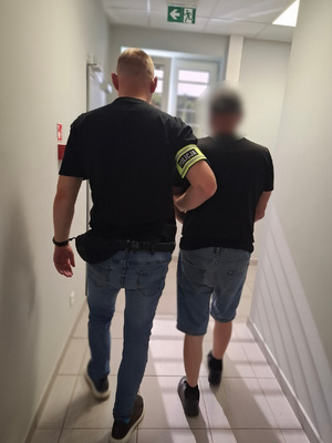 policjant podczas doprowadzania zatrzymanego
