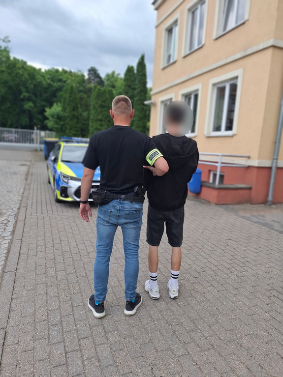 policjant podczas doprowadzania zatrzymanego