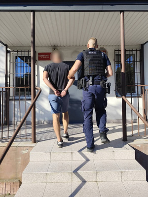 policjant podczas doprowadzania zatrzymanego