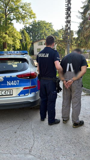 policjant podczas doprowadzania zatrzymanego