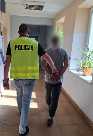 policjant podczas doprowadzania zatrzymanego