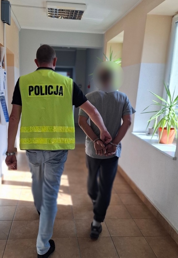 policjant podczas doprowadzania zatrzymanego