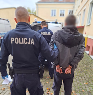 policjant podczas doprowadzania zatrzymanego