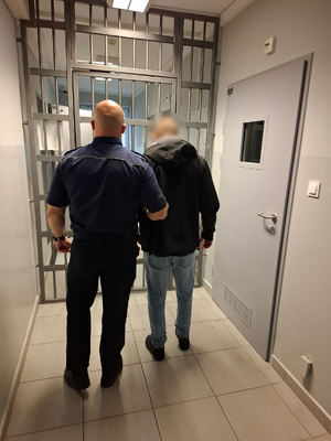 policjant podczas doprowadzania zatrzymanego